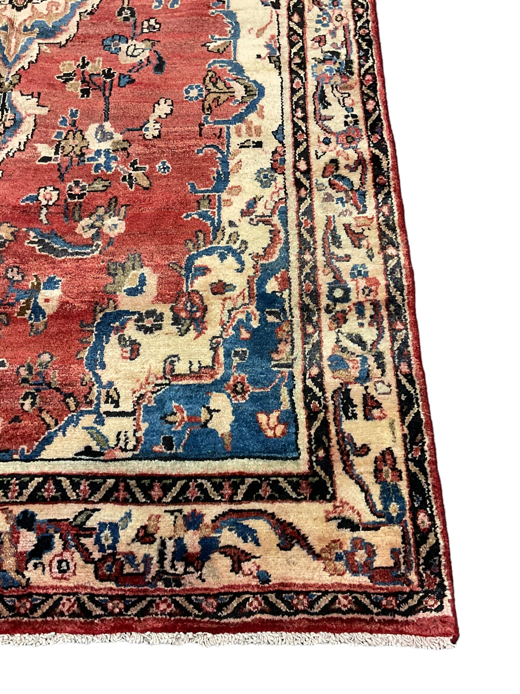 Persian Mahal red ground rug, central floral design pole medallion on a field decorated with flowerheads and foliage, the border decorated with trailing leafy branch and flowerheads 