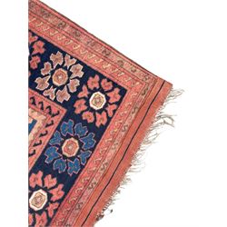 Afghan rust ground carpet, large central lozenge medallion decorated with stylised plant motifs, running water guard stripes enclosing indigo ground border decorated with stylised flower heads