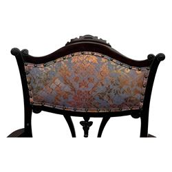 Late Victorian mahogany framed armchair, upholstered in muted purple fabric with iridescent floral pattern and nailhead trim, central foliate carved splat over padded scrolled arms, on cabriole supports fitted with castors