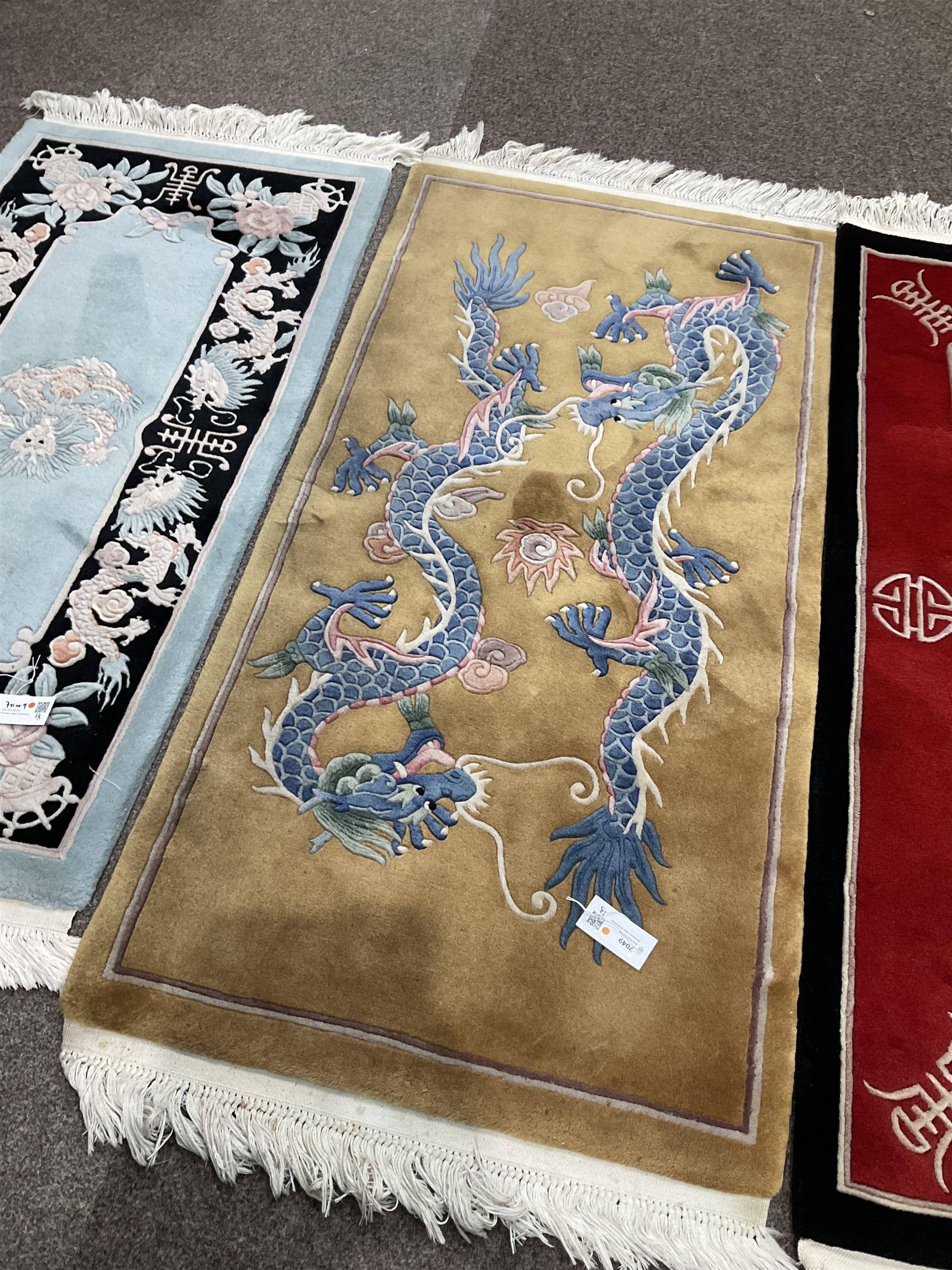 Collection of four Chinese washed woollen rugs - blue ground (153cm x 92cm); red and black ground (156cm x 94cm); light blue ground (138cm x 70cm); gold ground (153cm x 77cm)