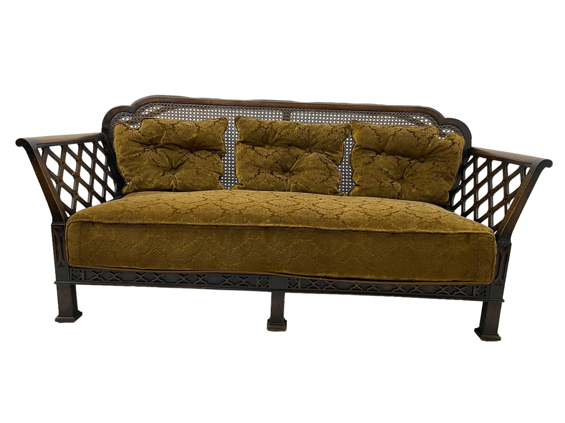 Early 20th century three-piece bergère suite - three seat sofa (W177cm, H82cm, D75cm); pair of matching armchairs (W84cm); single caned back with 'cock-pen' panelled arms, upholstered in foliate pattern fabric, blind fretwork lower frieze over square feet 