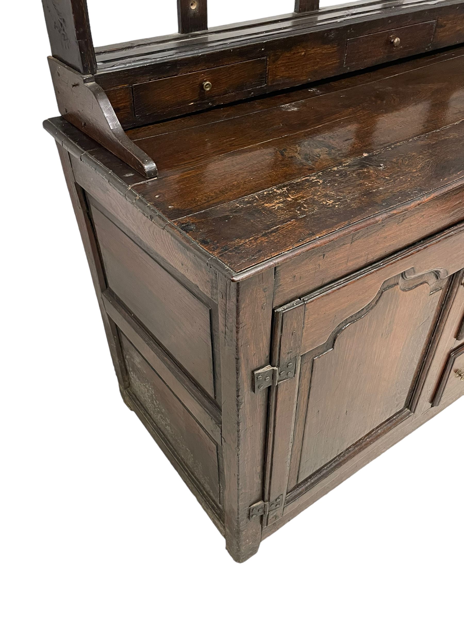 18th century oak dresser, projecting cornice over three heights plate rack with three small drawers, rectangular ovolo-moulded top over three central drawers and two flanking cupboards, enclosed by fielded panelled doors, on stile supports 