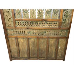 Early 20th century Javanese teak and hardwood door panel or room divider, rectangular panelled form with moulded frame and pegged construction, carved and pierced with scrolling decoration and flower head motifs, shaped and pierced splats with interlocking pattern