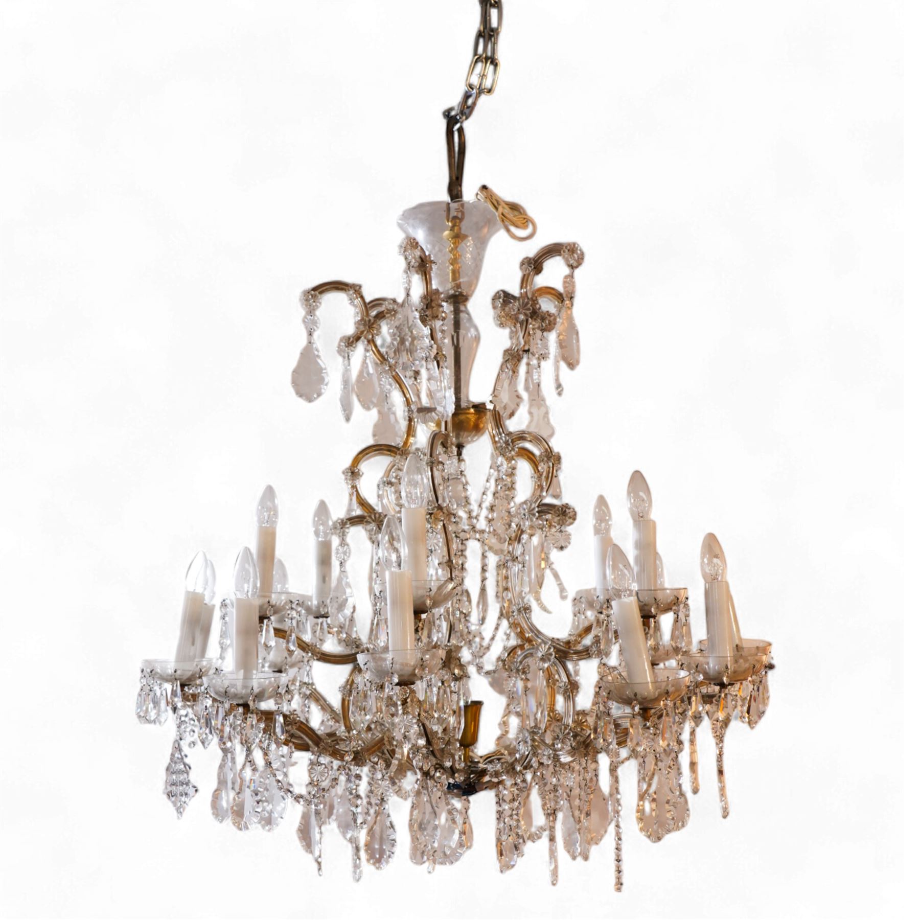 Large mid-to-late 20th century two-tier glass chandelier, shaped body dish over glass column, serpentine metal frame supporting fifteen branches, the frame clad with glass panels and decorated with drop pendants, each branch with glass bobeche decorated with drop prisms 