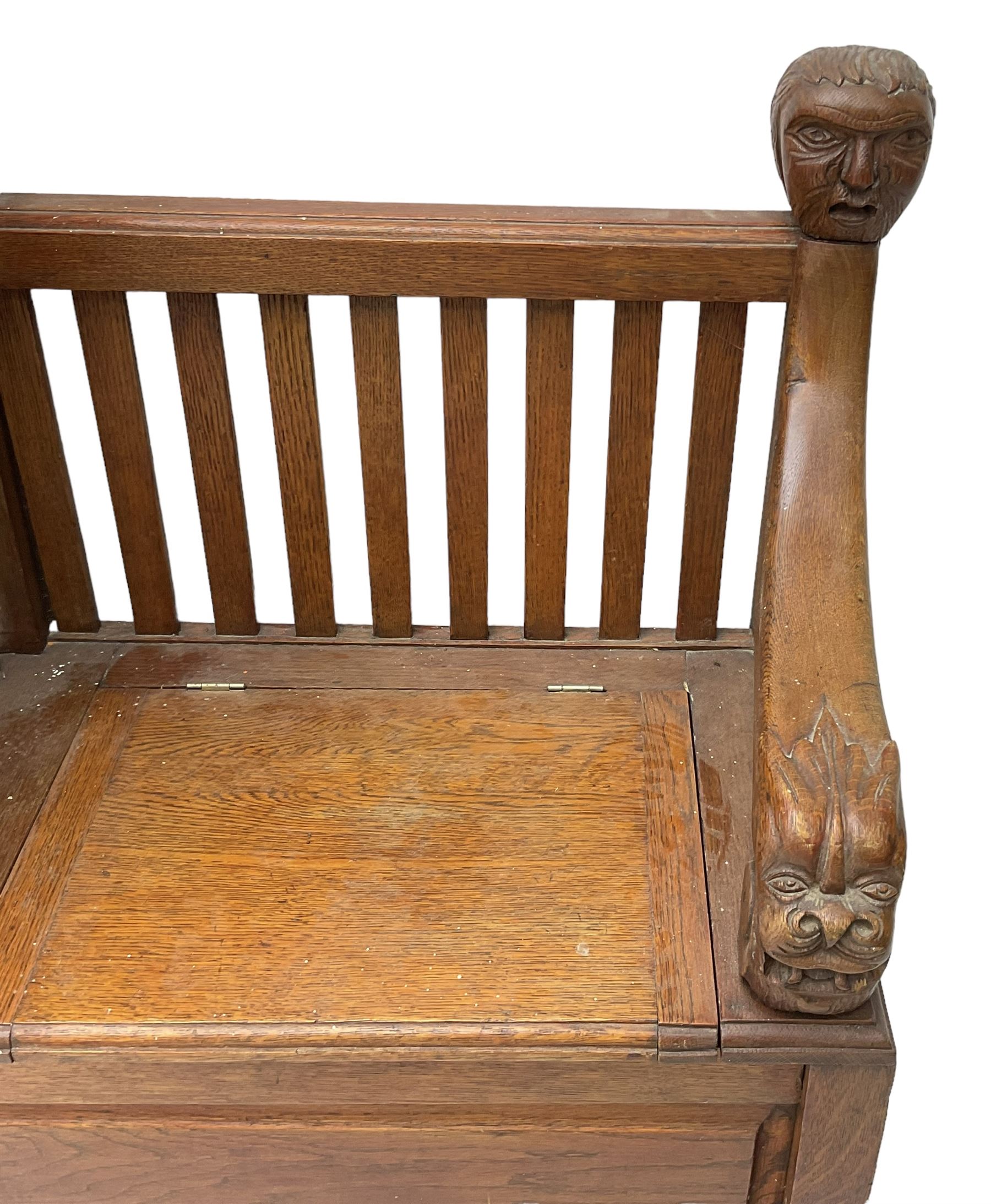 Victorian carved oak hall bench, raised shaped pediment carved with acorns and oak leaves, hinged lid over stick and umbrella stand with drip tray, fitted with a series of vertical rails, hinged and panelled box seat, carved with grotesque masks 