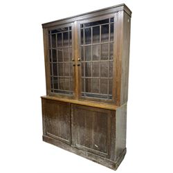 20th century beech bookcase on cupboard, the top section enclosed by two glazed doors, the lower section enclosed by two panelled doors, on plinth base