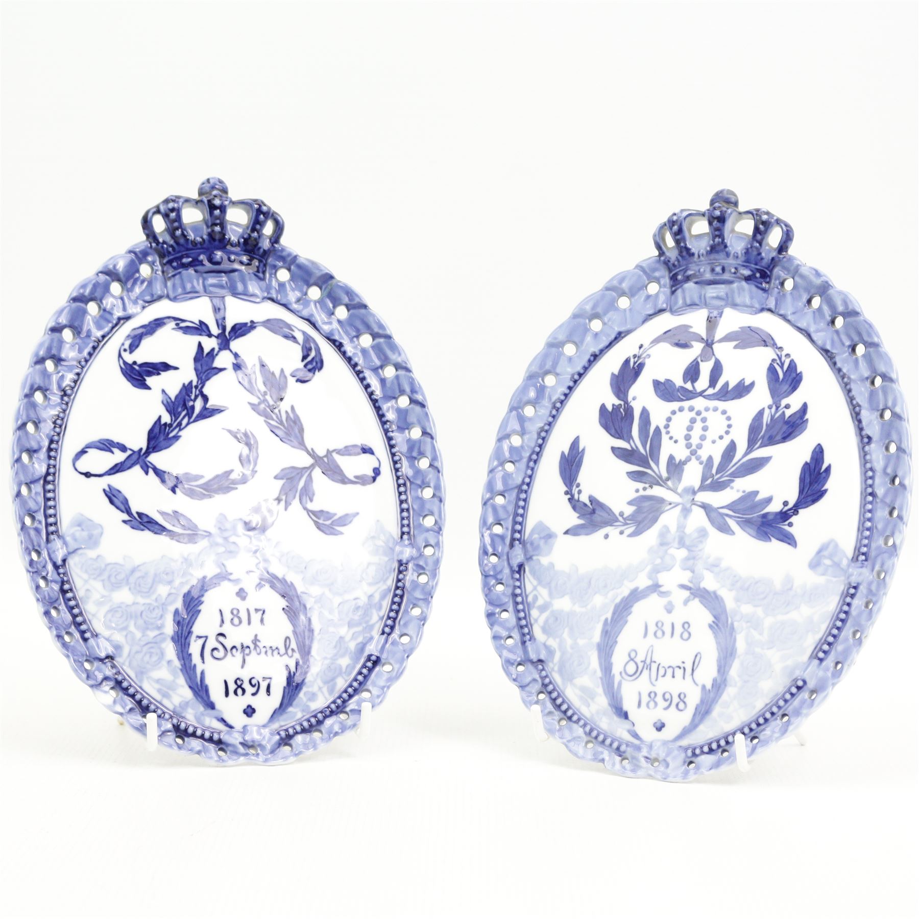 Two Royal Copenhagen commemorative oval plaques, the first dated 1818-1898 produced to celebrate King Christian IX's 80th birthday, the second dated 1817-1897 and celebrates Queen Louise's 80th birthday, both with crown finials, L23.5cm (2)