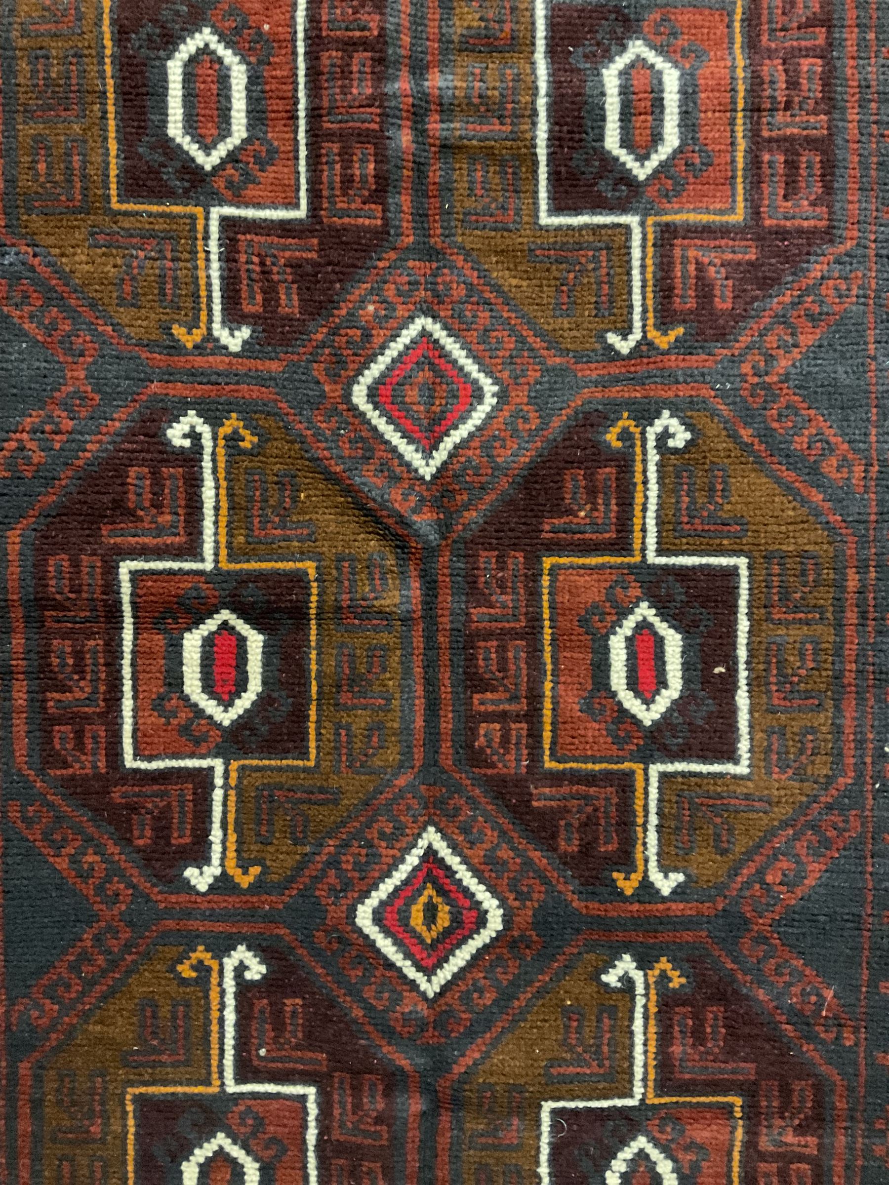 Baluchi red and blue ground rug, the field decorated with large six Gul motifs