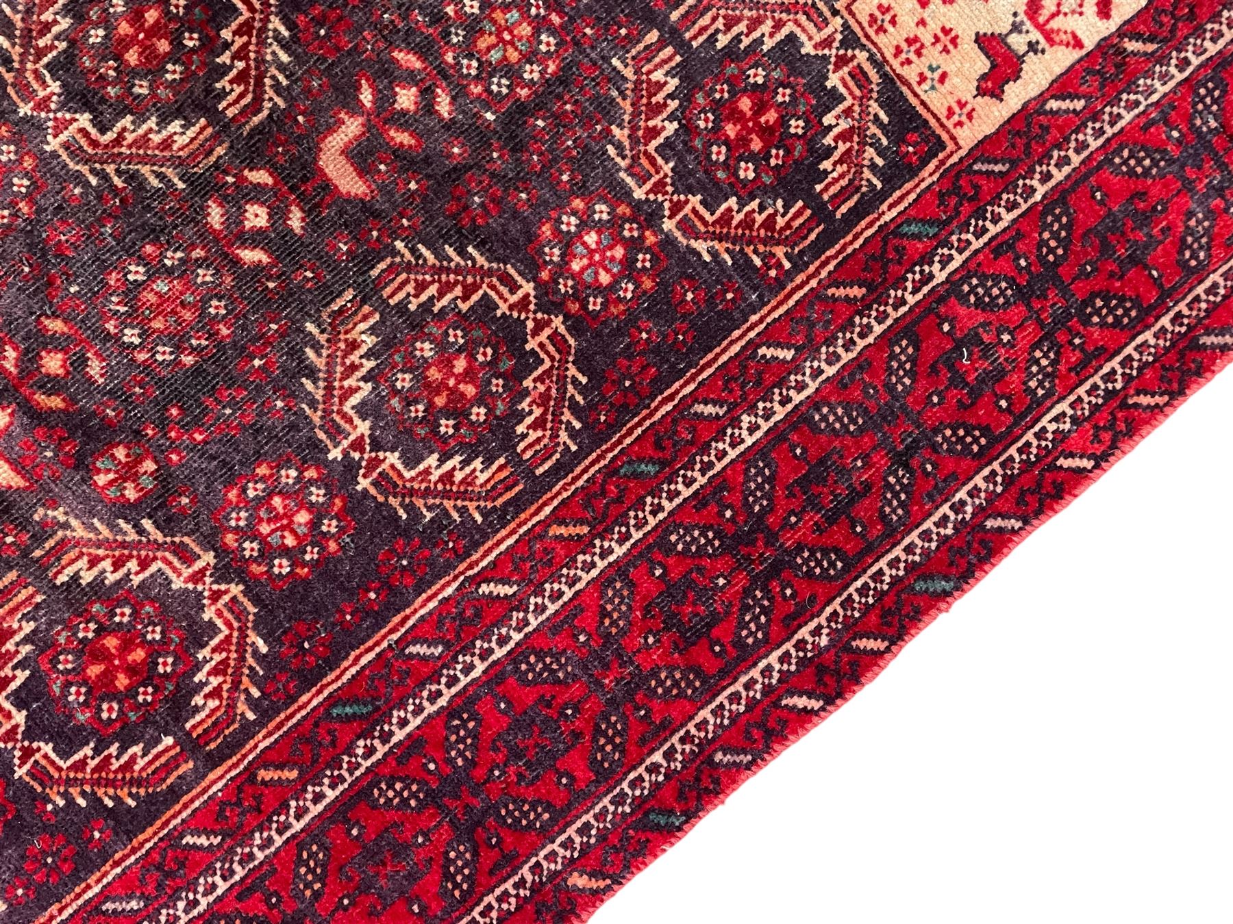 Persian Baluchi dark indigo and crimson ground rug, the field decorated with rows of repeating Pitrak motifs and surrounded by small bird and flower head motifs, floral urn decorated spandrels, repeating Pitrak border within guard stripes