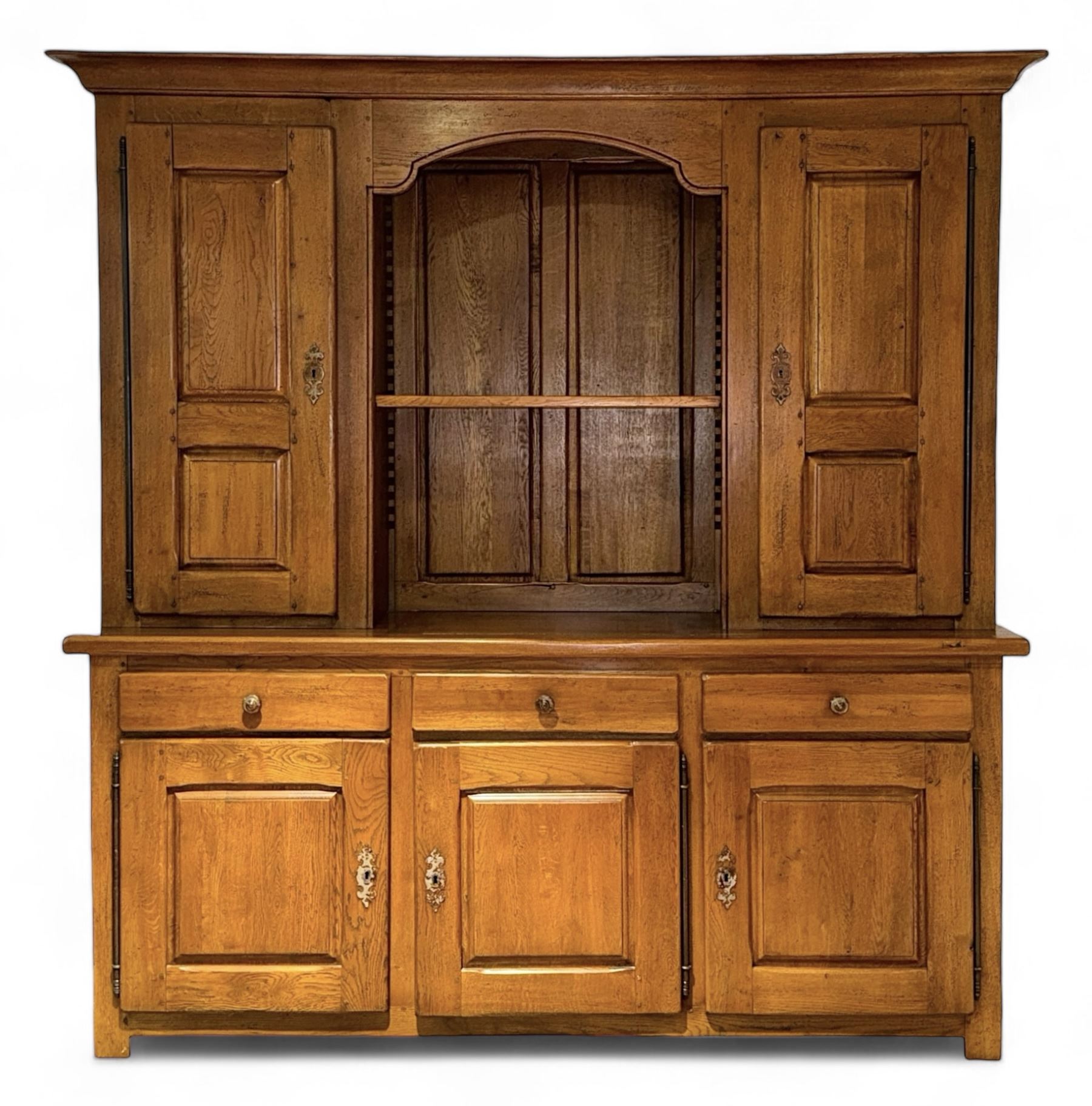 Large 20th century oak dresser, projecting cornice over open arched central section with two shelves, flanked by two panelled cupboards with two shelves, lower section with three drawers above three cupboards, on stile supports 