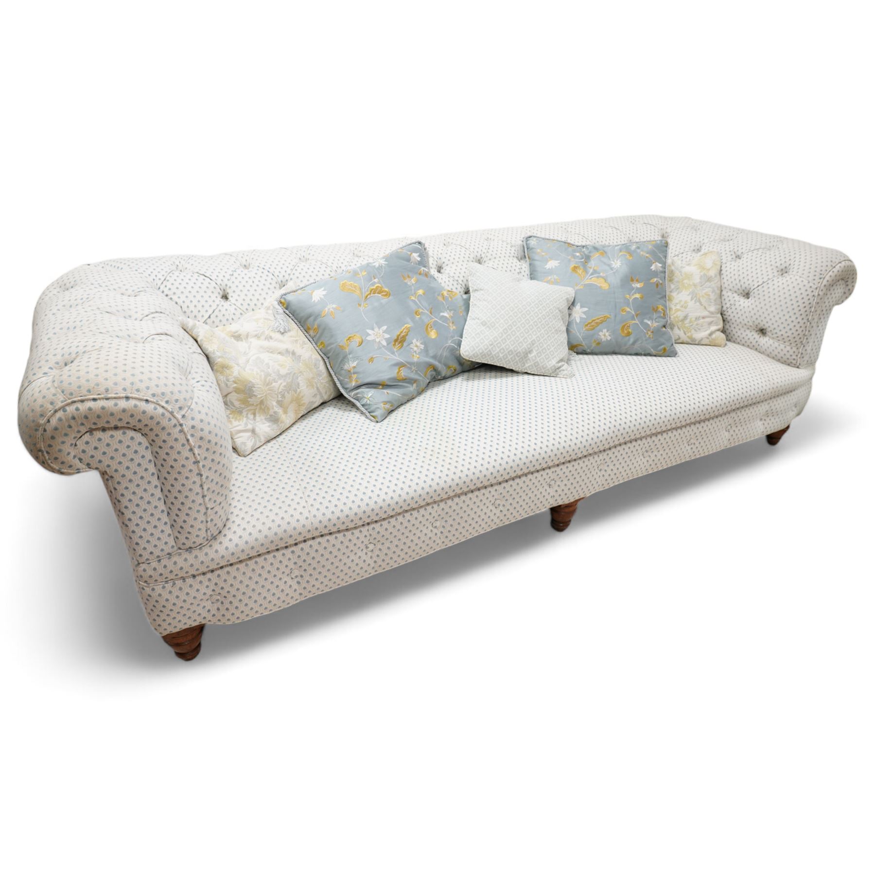 Victorian oak framed three seat Chesterfield sofa, traditional shape, upholstered in deep buttoned ivory and blue patterned fabric, raised on turned feet, with loose scatter cushions