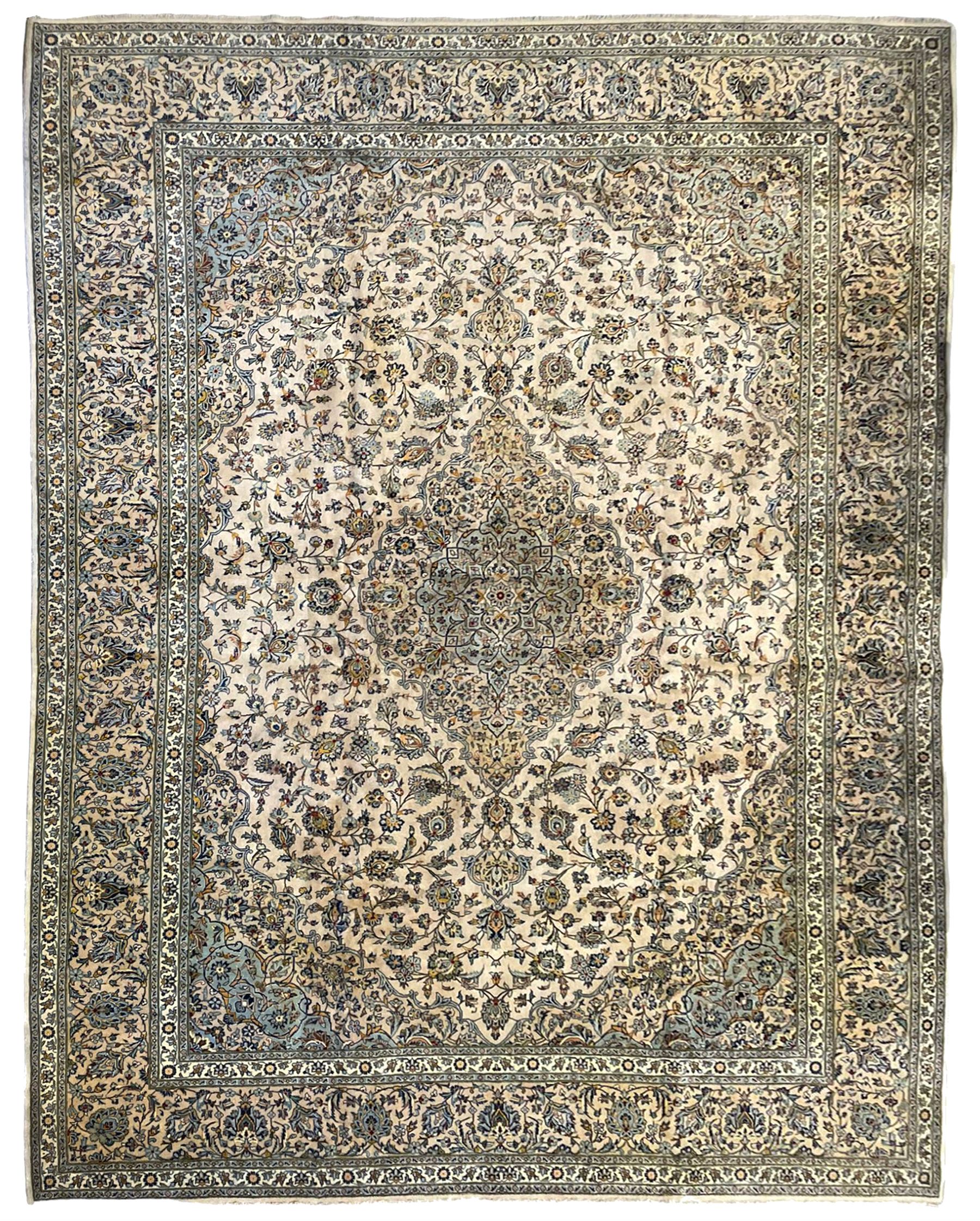 Central Persian Kashan pale khaki ground carpet, shaped central medallion enclosing small stylised motifs, the field decorated profusely with trailing foliate branches and plant motifs, guarded border with repeating floral design 