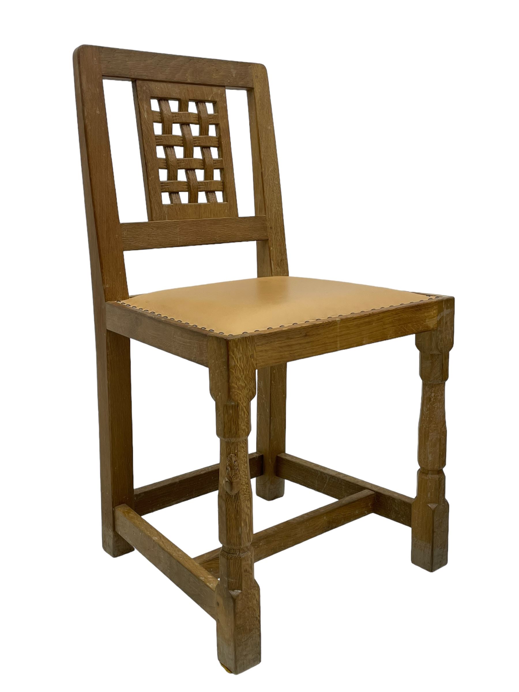 Mouseman - set of six oak dining chairs, pierced and carved lattice panel back over tan leather seat with studded band, on octagonal front supports united by plain H stretchers, carved with mouse signature, by the workshop of Robert Thompson, Kilburn 