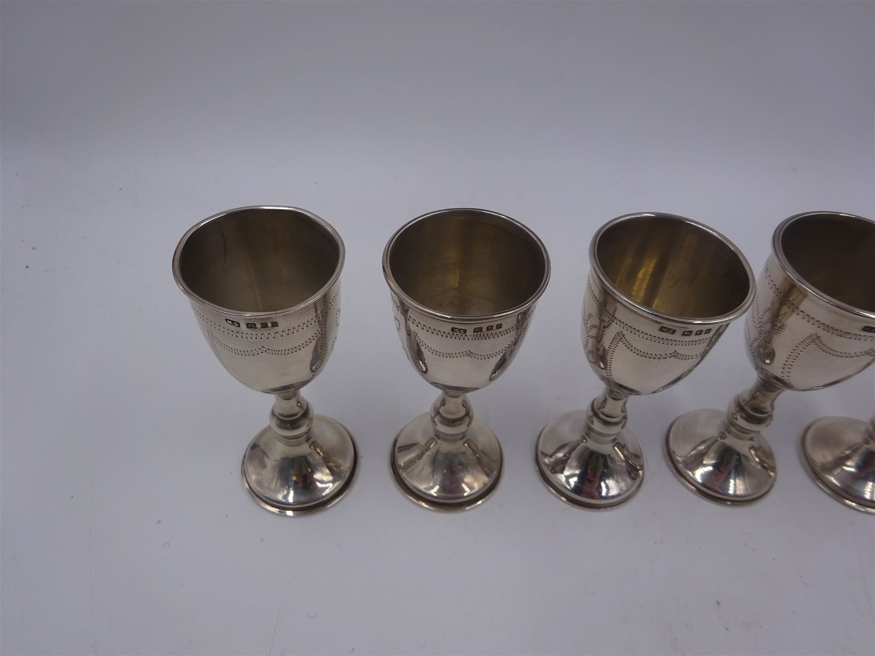 Set of six 1920s silver Kiddush cups, of goblet form with knopped stem, and engraved foliate detail, hallmarked London 1929, maker's mark M.S, H9cm