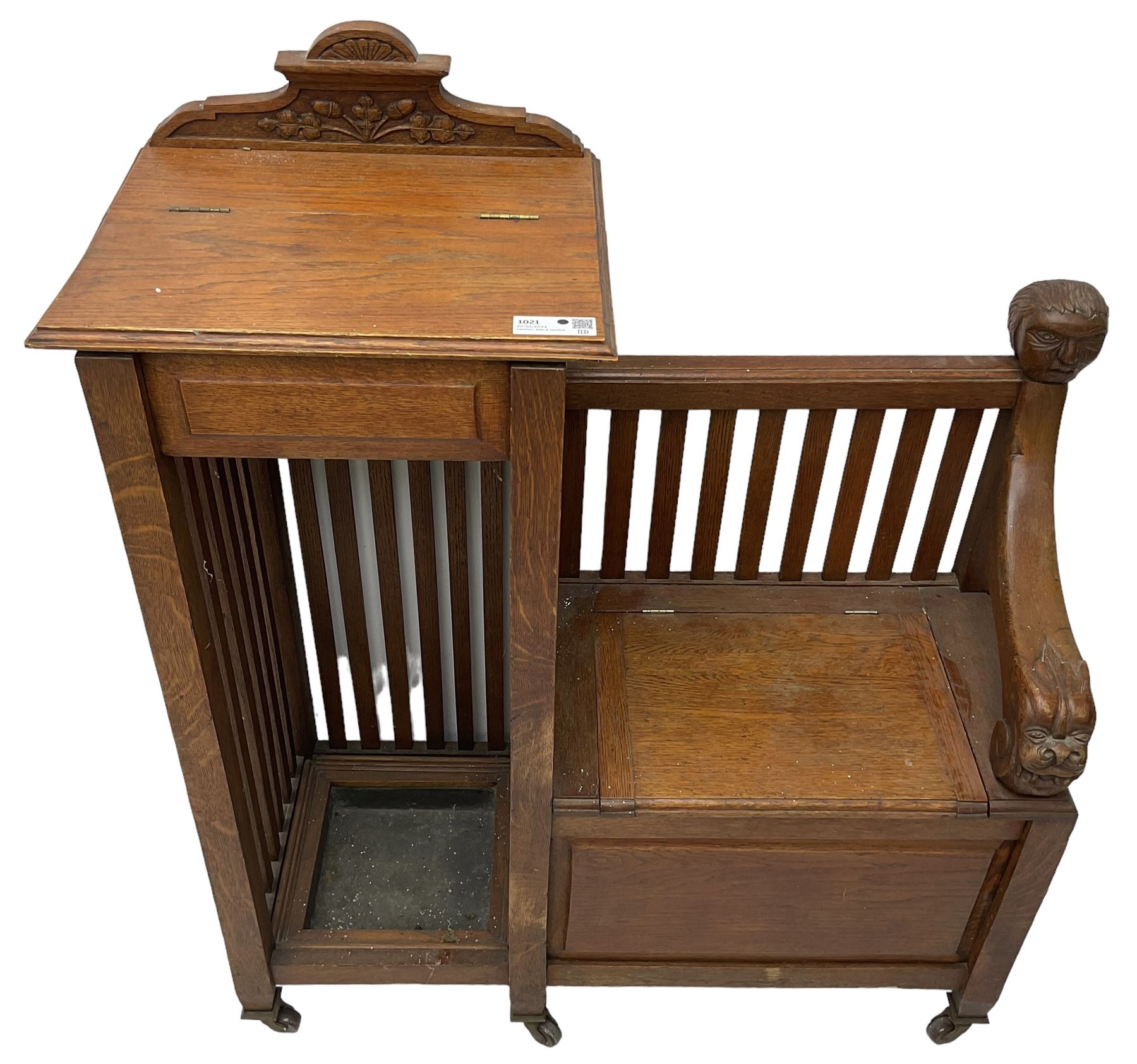 Victorian carved oak hall bench, raised shaped pediment carved with acorns and oak leaves, hinged lid over stick and umbrella stand with drip tray, fitted with a series of vertical rails, hinged and panelled box seat, carved with grotesque masks 