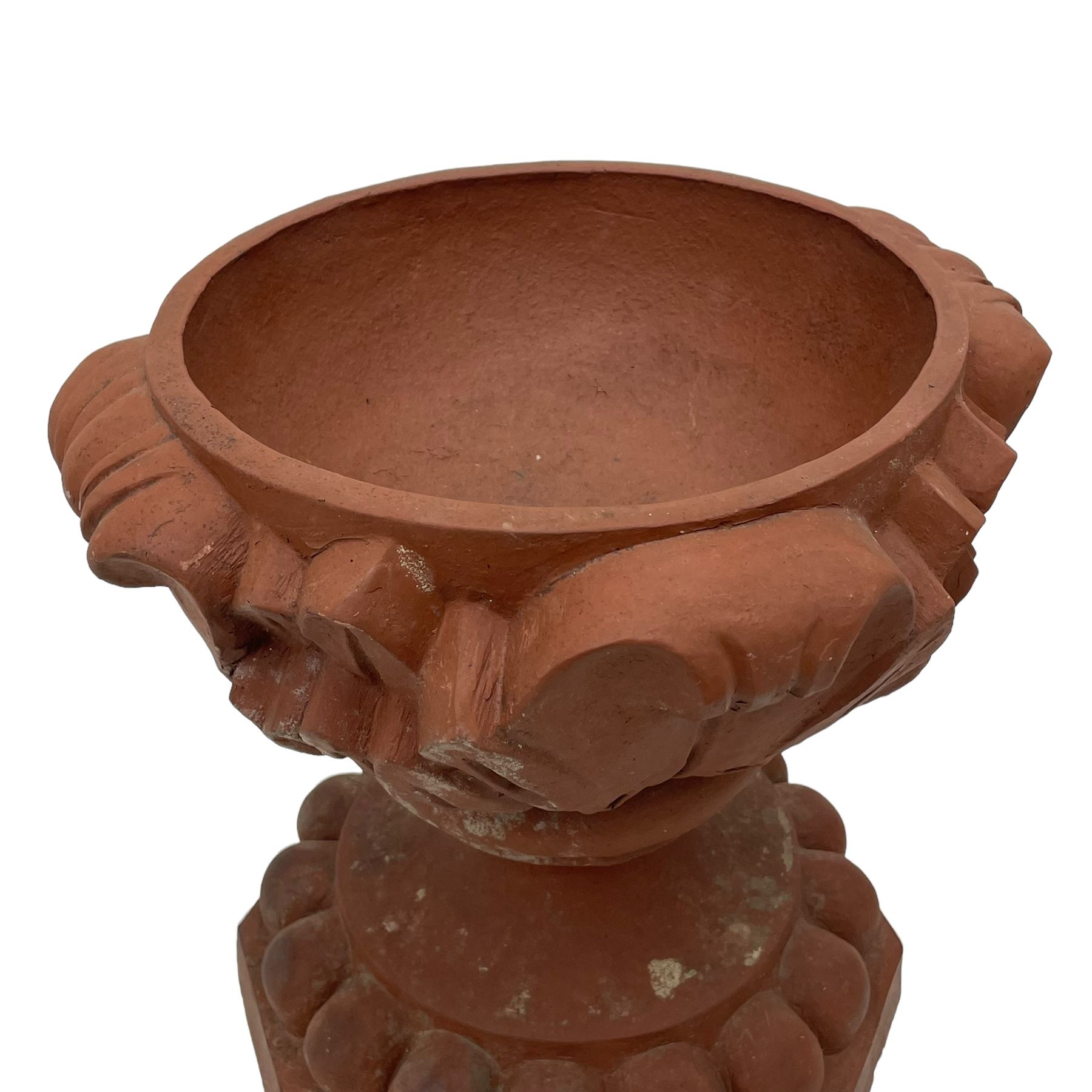 Pair of late 19th to early 20th century red terracotta garden urn planters, the shallow bowls moulded with curled acanthus leaf decoration, on circular foot with globular beaded moulding, octagonal base