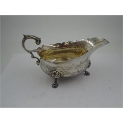 1930s silver sauce boat, of typical form with shaped rim, and acanthus leaf capped flying scroll handle, upon three palmette mounted stepped feet, hallmarked 	Harrods Ltd, London 1934, including handle H10.4cm