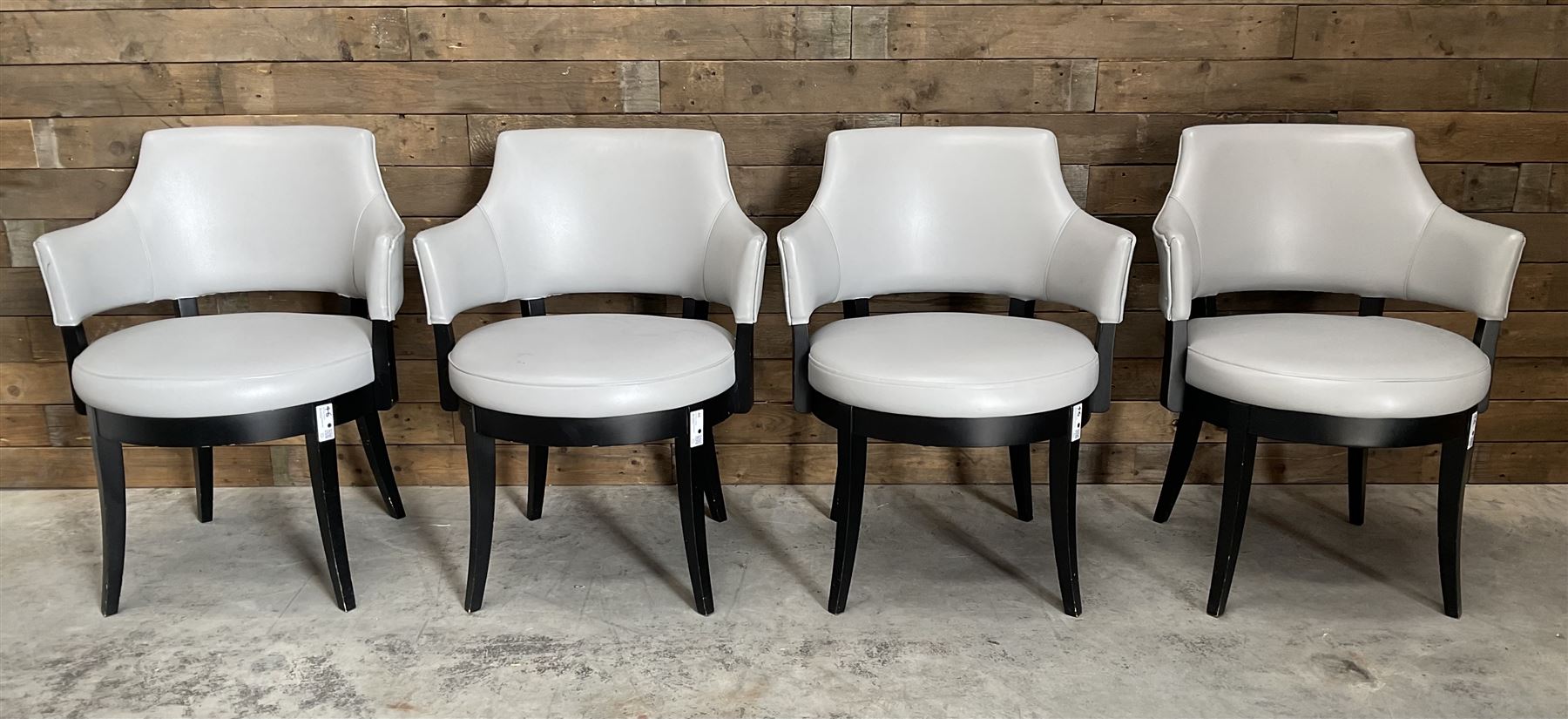 Four ebonised framed tub shaped armchairs, upholstered in grey fabric