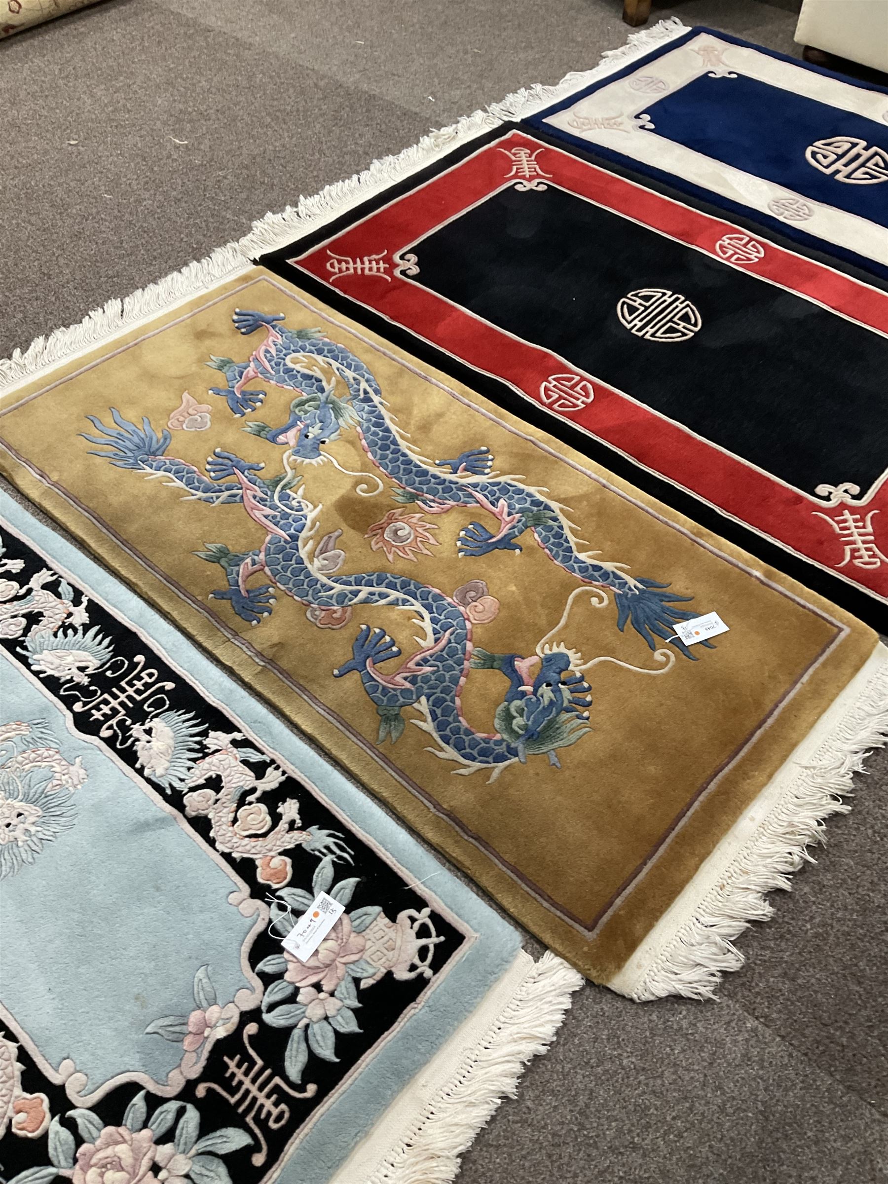 Collection of four Chinese washed woollen rugs - blue ground (153cm x 92cm); red and black ground (156cm x 94cm); light blue ground (138cm x 70cm); gold ground (153cm x 77cm)