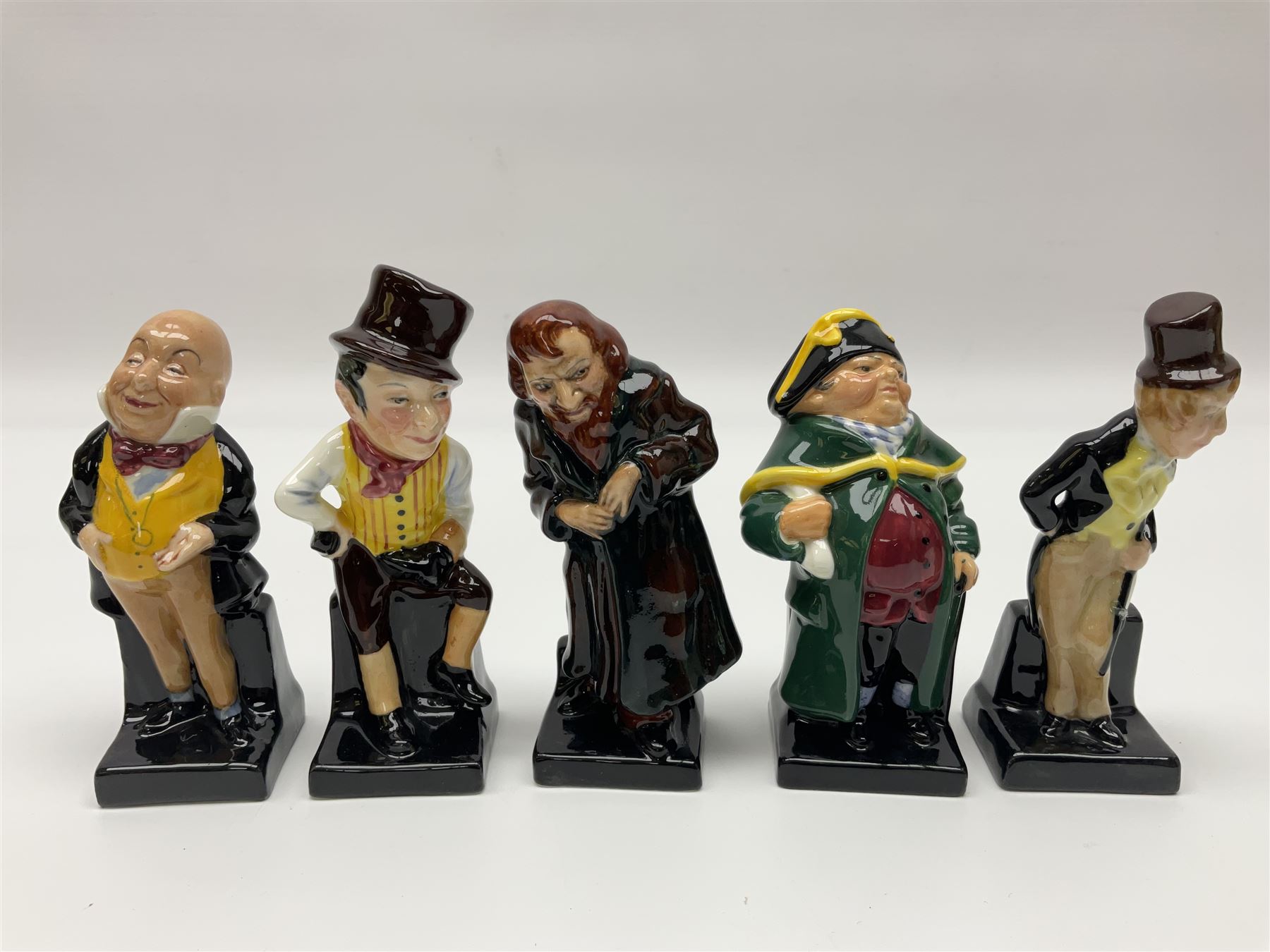 Twenty four Royal Doulton figures of characters from the works of Charles Dickens, to include Sam Weller, Pecksniff, Oliver Twist, Sairey Gamp, Artful dodger etc