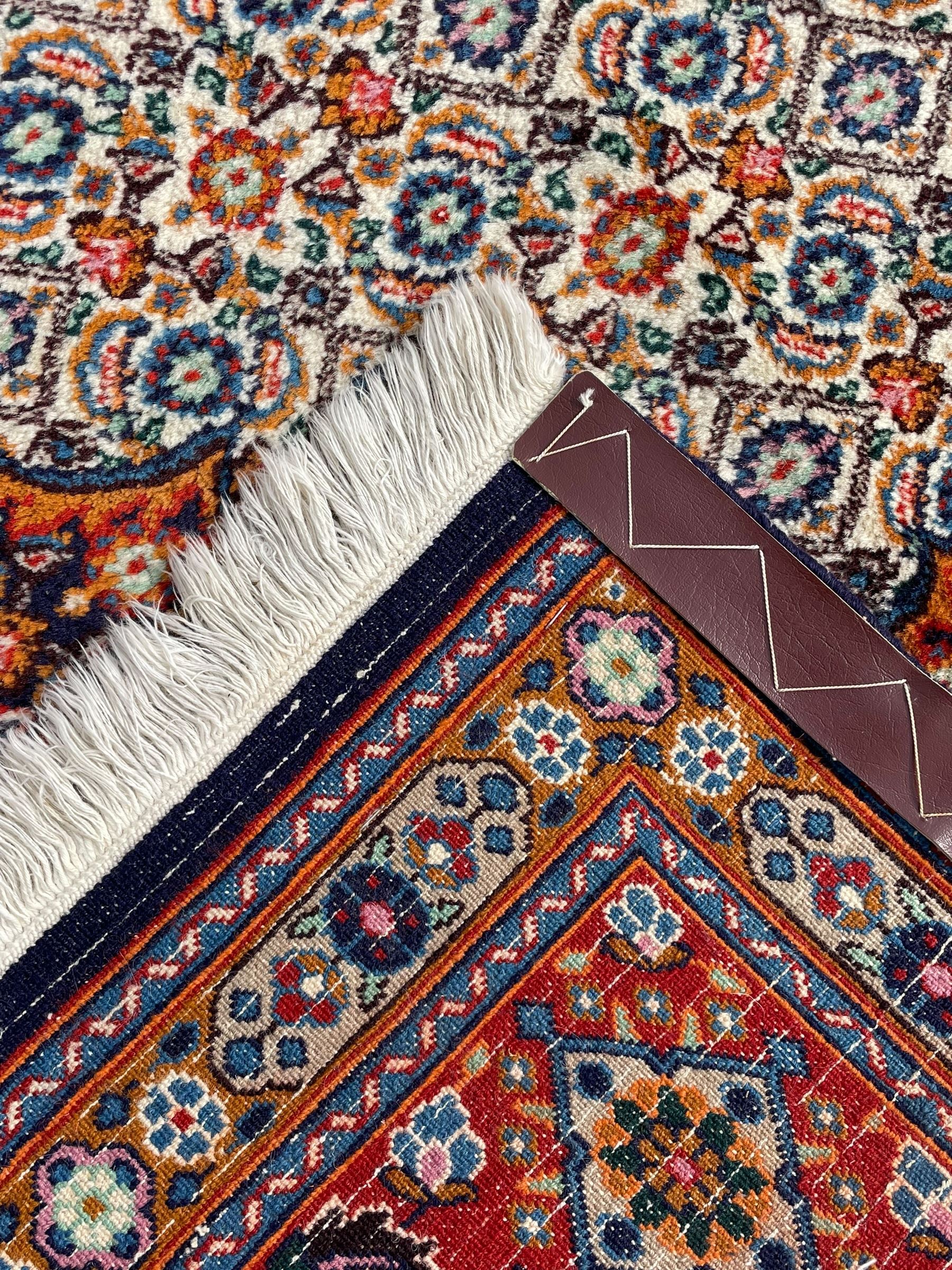 Persian Bidjar ivory and indigo ground rug, large central rosette medallion surrounded by floral herati motifs, crimson ground border decorated with repeating palmettes, within guard stripes decorated with small flower head motifs 