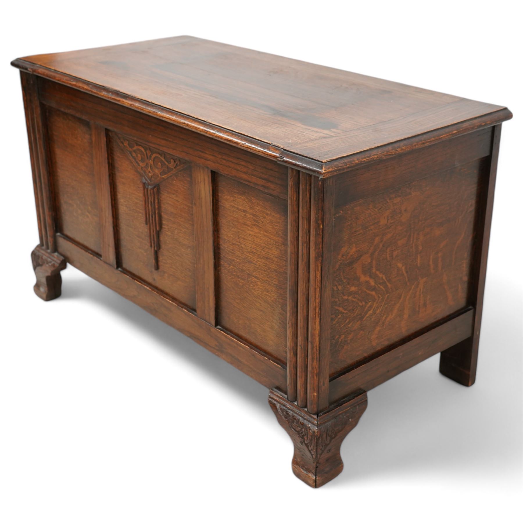 Early 20th century oak blanket chest, rectangular hinged top over triple panelled front with moulded decoration, on foliate carved ogee feet