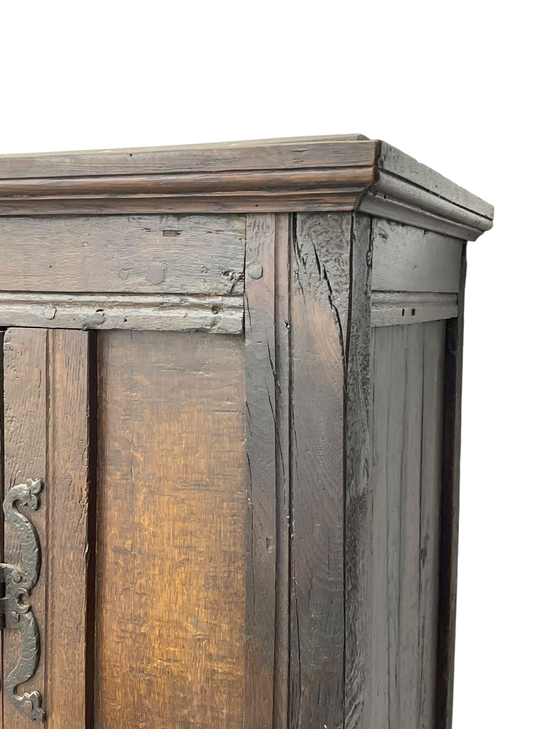 17th century and later oak hall cupboard, panelled front and sides with moulded frame, enclosed by single door with wrought metal hinges and handle, the interior fitted with hooks, on stile supports 