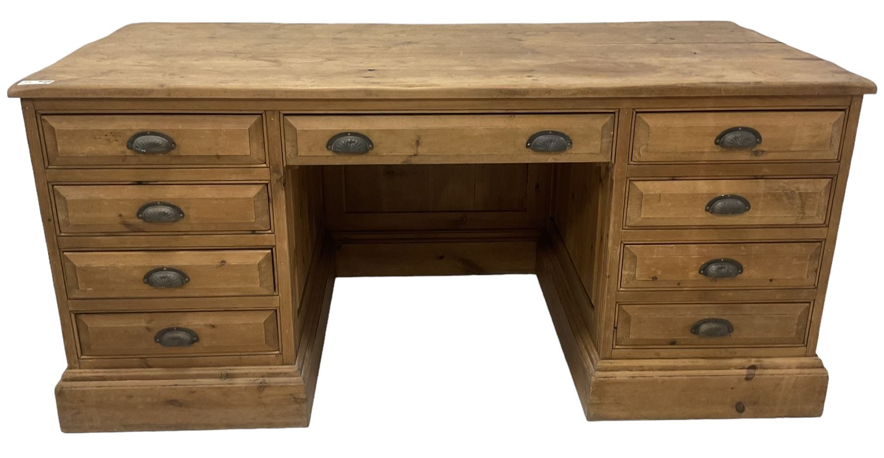 20th century waxed pine kneehole desk, rectangular top over nine drawers with cup handles, on moulded plinth base