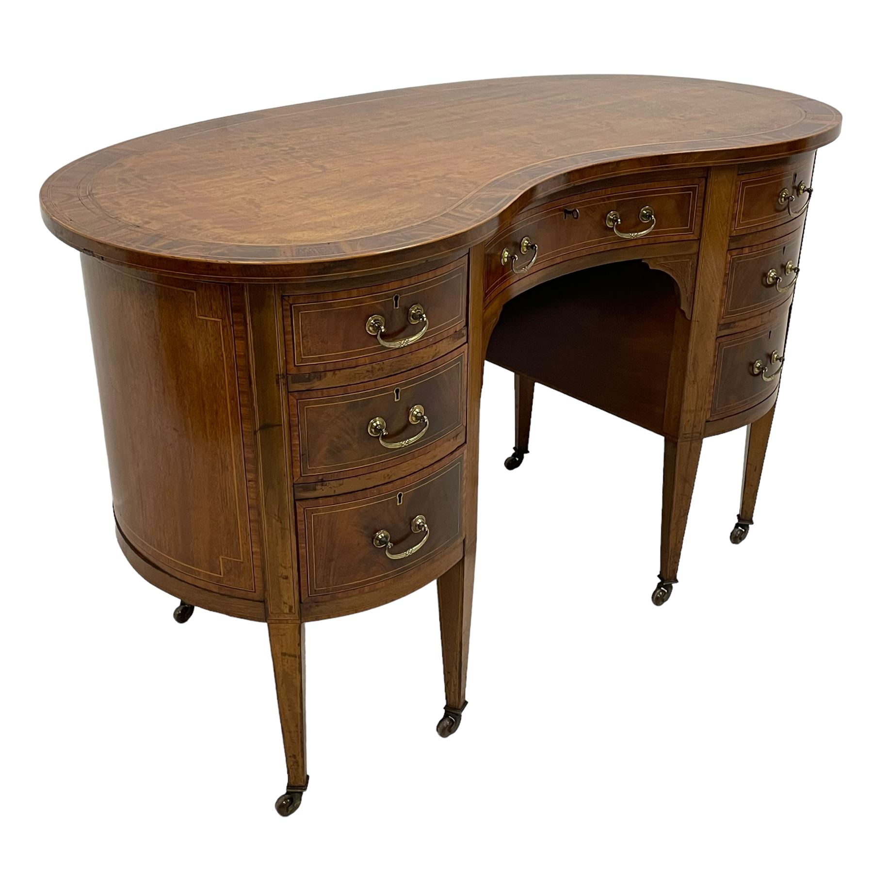 Edwardian mahogany and satinwood banded kidney-shaped writing desk, the shaped top with figured mahogany banding and boxwood stringing, fitted with seven drawers with satinwood bandings, on square tapering supports with brass and ceramic castors