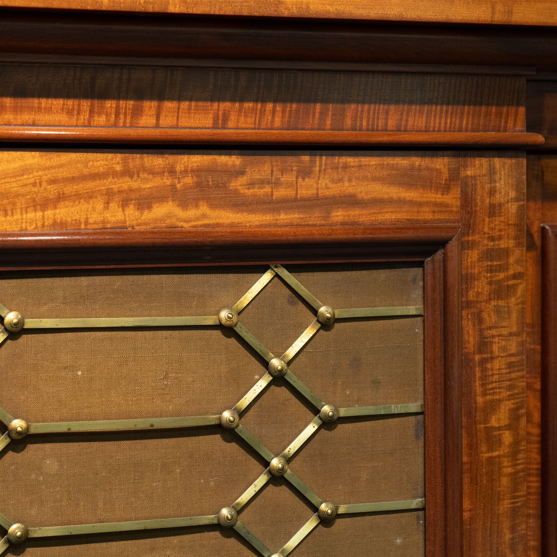 Large 19th century figured mahogany bookcase, enclosed by five brass grille panel doors, the interior fitted with adjustable shelves, double drop centre and break front with raised stepped tops, on plinth base 