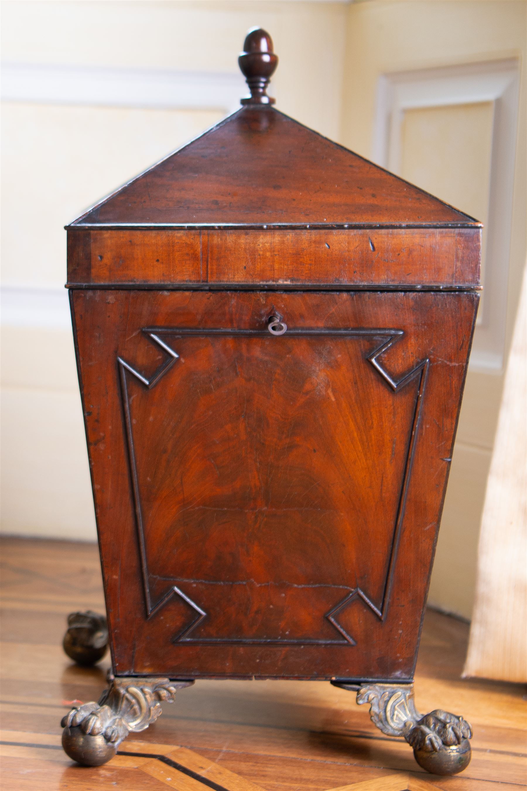 George III mahogany wine cooler or cellarette, the pointed hinged lid with turned final, square tapering body with applied geometric mouldings, on gilt metal and foliate cast ball and claw feet, with metal liner 