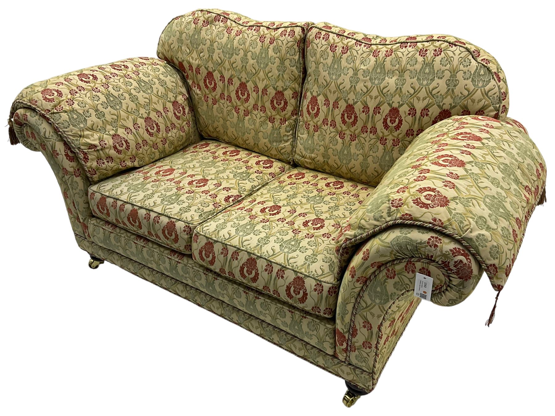 Traditional design two seat sofa, high back with scrolled arms, upholstered in beige fabric with red and green damask motifs, on castor supports (L178cm, D100cm, H89cm); matching armchair (L109cm, D89cm, H89cm)