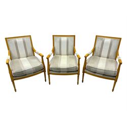 Three mid-20th century beechwood fauteuil armchairs, upholstered backrest and seat in cream stripe fabric, padded armrests with scroll detail, on tapered fluted supports with carved floral rosette blocks