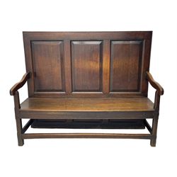 18th century oak settle, the high back with three fielded panels, shaped arms and solid plank seat, standing on square supports joined by stretchers