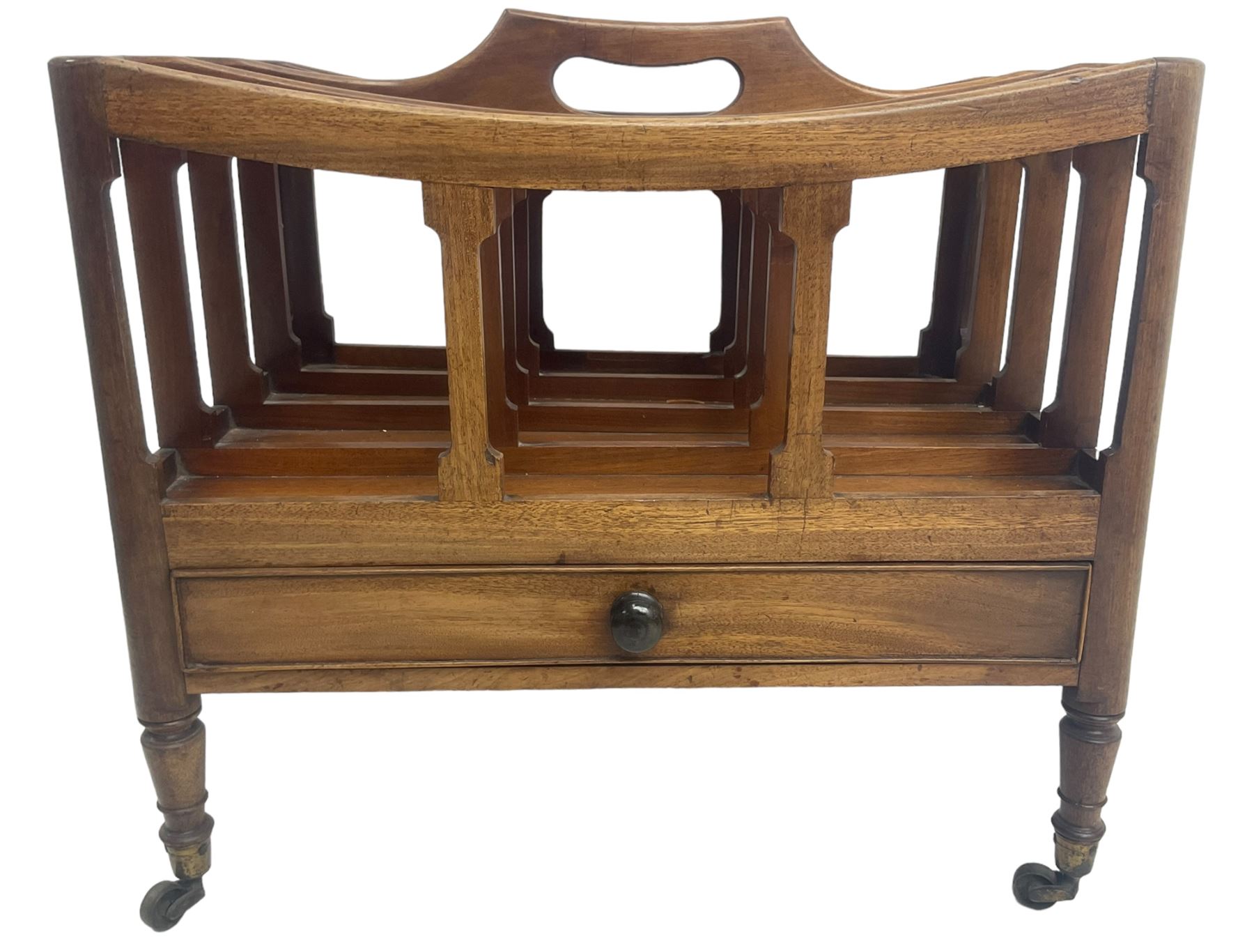 George III mahogany four-division Canterbury, the concave shaped dividers with a central pierced handle, over a single cock-beaded drawer, raised on turned supports terminating in brass cups and castors