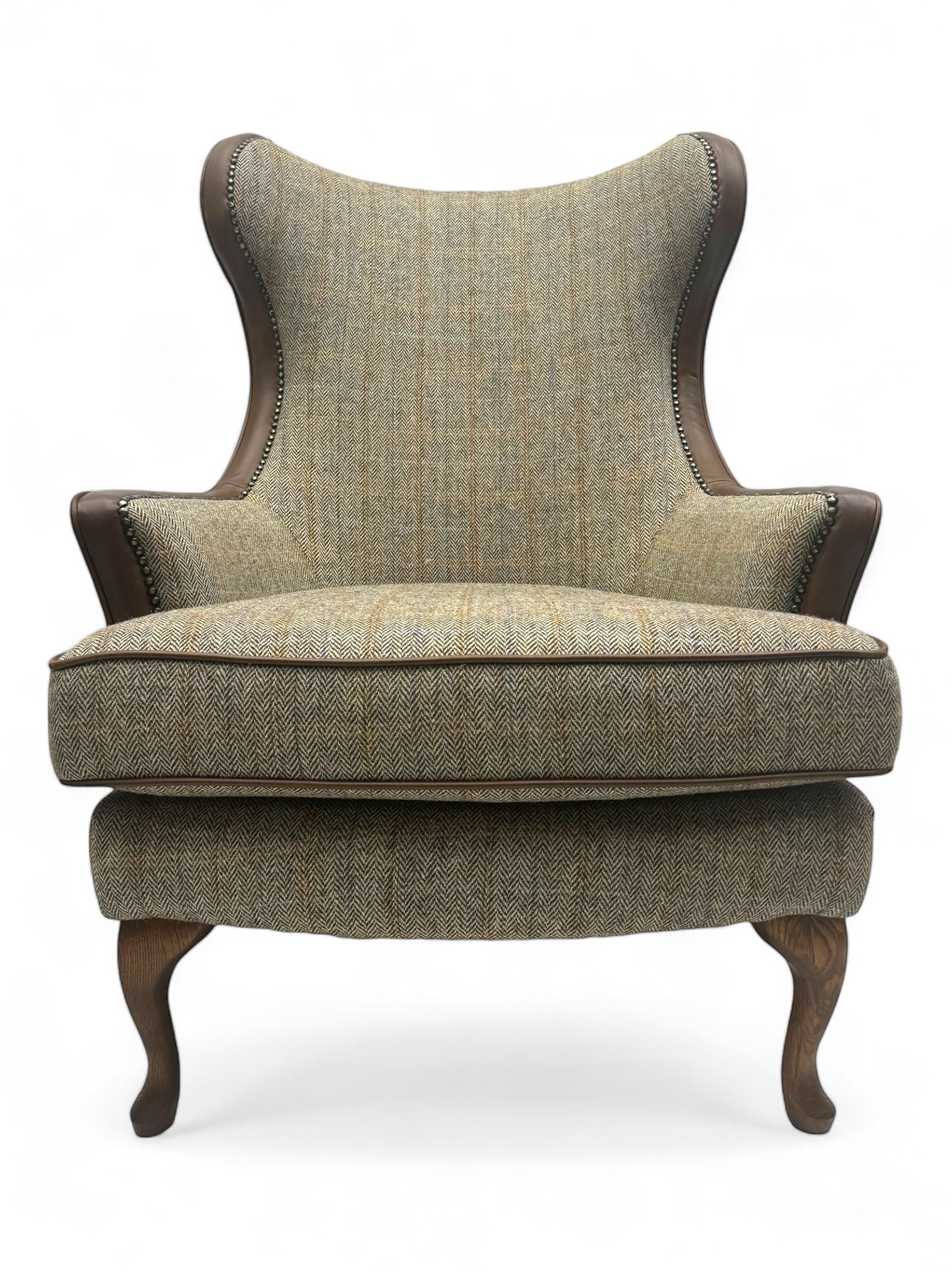 Wood Bros - contemporary wingback armchair, high back with curved wings upholstered in herringbone patterned fabric, accented with leather trim and brass nailhead studs, resting on cabriole front feet 