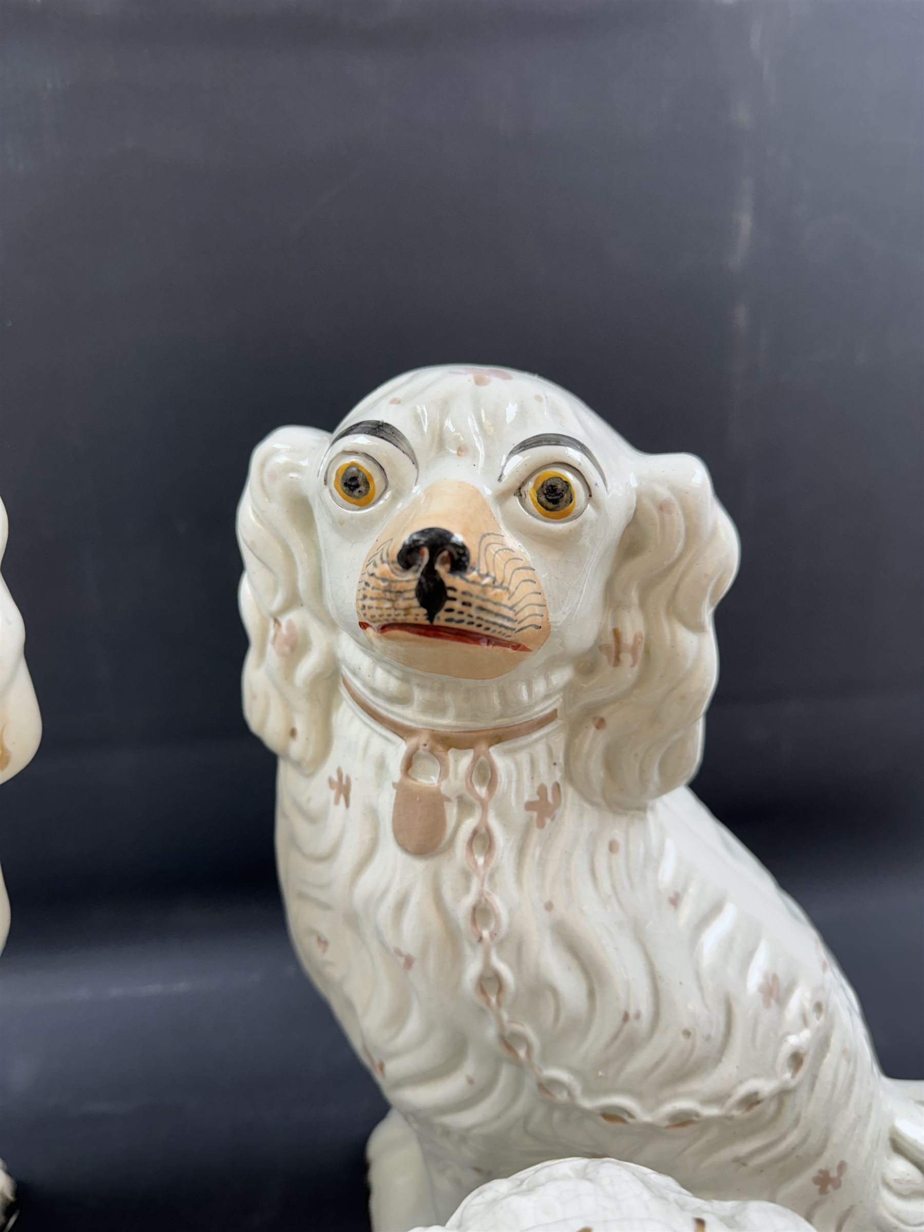 Staffordshire and Staffordshire style figures, to include a chained hound upon a blue oval base in the manner of Samuel Alcock, two pairs of seated Spaniels, a pair modelled as male figure and milk maid with cows, pair of recumbent Greyhounds, etc.