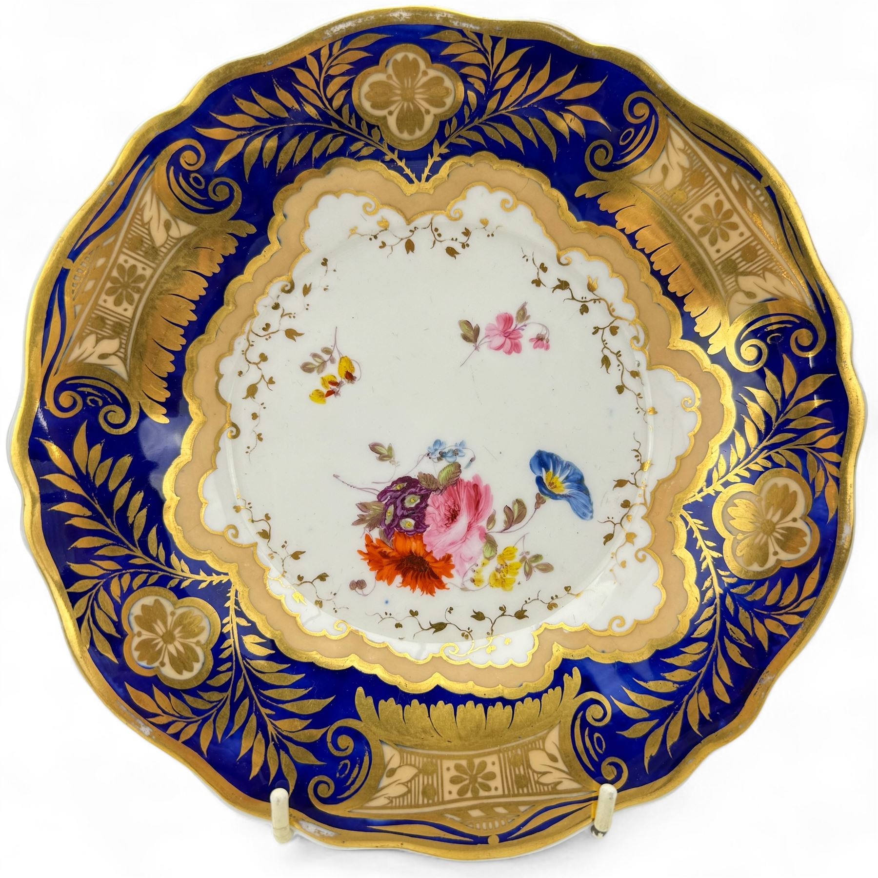 Pair of early 19th century plates, each painted with summer flowers within gilt fan shaped reserves, against a blue scale ground, unmarked, D19cm, together with a 19th century English porcelain plate, pattern no. 2/1078 (3)