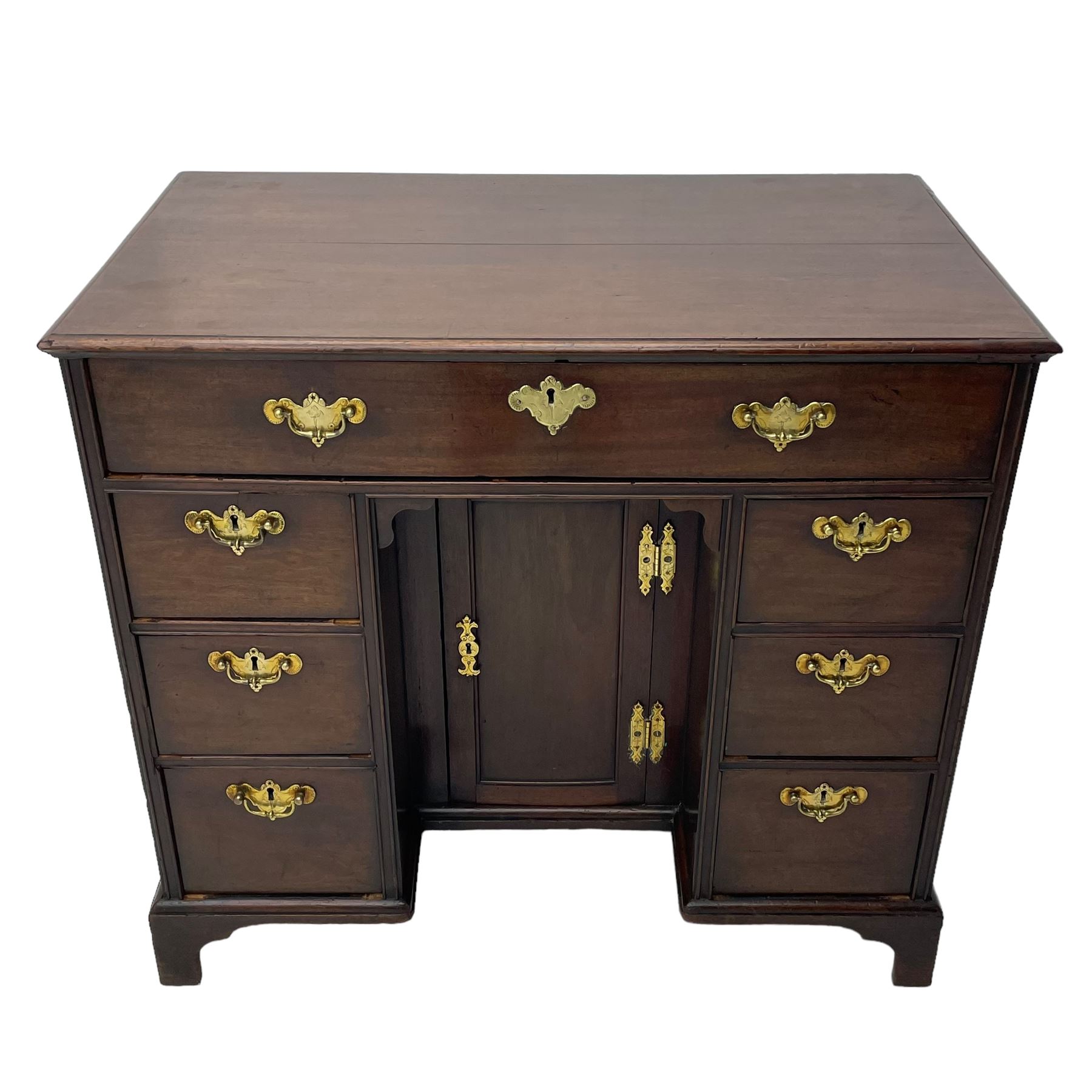 George III mahogany kneehole desk, moulded rectangular top over one long drawer, six short drawers and recessed panelled cupboard, cock-bead moulded frame, fitted with shaped brass handle plates with engraved decoration, on bracket feet 