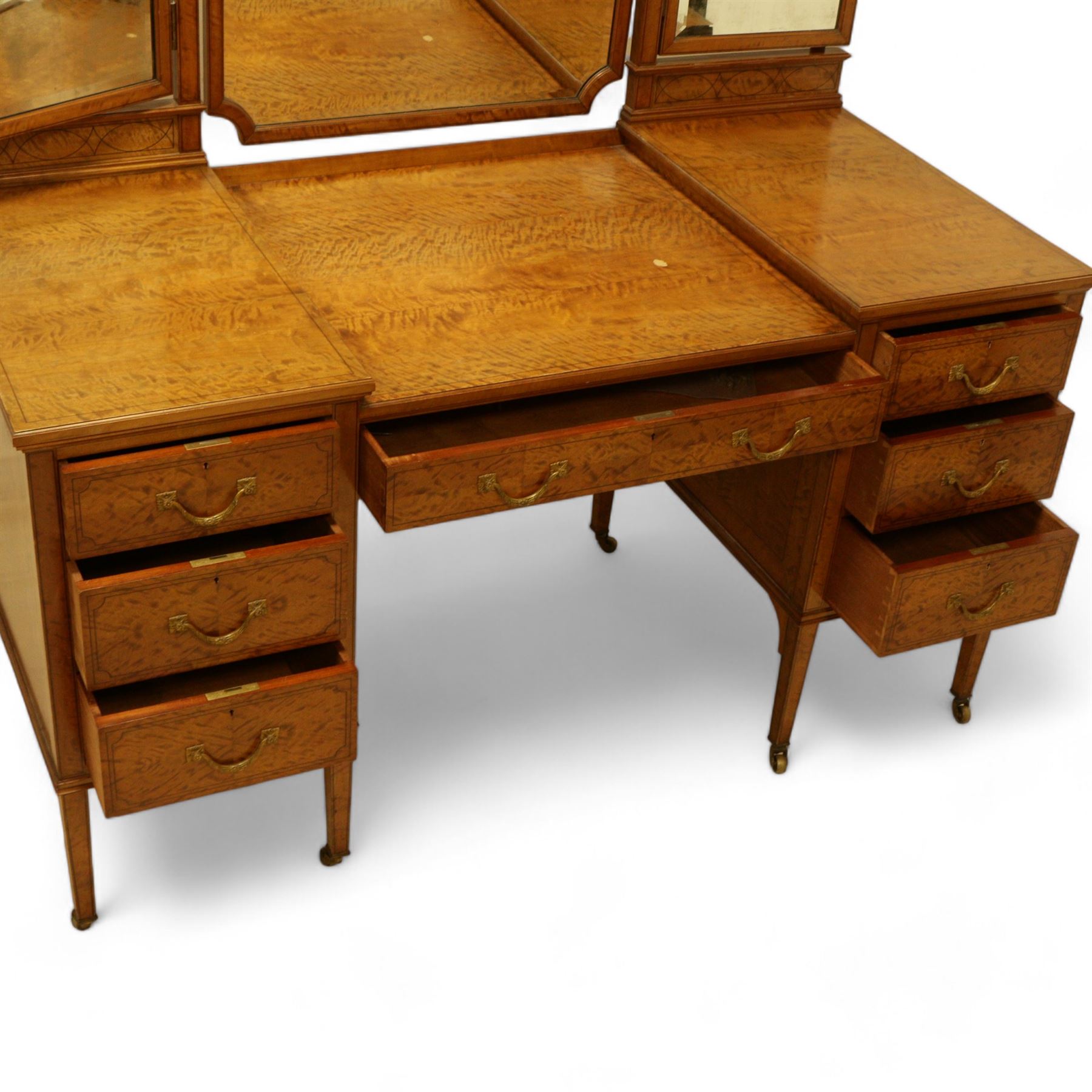 Waring & Gillow Ltd. - Edwardian satinwood dressing table, raised bevelled triple mirror back on square supports, over frieze inlaid with geometric stringing in ebony, moulded drop-centre table with stringing, fitted with seven drawers, reeded and foliate cast handles and square leaf cast handle plates, on square tapering supports terminating to brass castors, the centre drawer with metal maker's plaque and maker's stamp for 'Waring & Gillow, Ltd.', the top three drawers fitted with Chubb locks, the remaining drawers fitted with locks stamped 'Gillows Lancaster', together with associated chair 