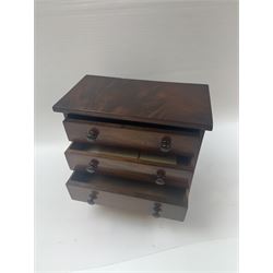 19th century mahogany miniature chest of drawers, with three graduating drawers, each with wooden handles, with inlaid shaped front and upon four bracket feet, H24cm