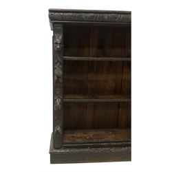 Victorian Jacobean revival carved oak open bookcase, cushion frieze carved with foliate decoration the pilasters decorated with applied carved lion masks and fruit motifs with extending leafage, two shelves over skirted base