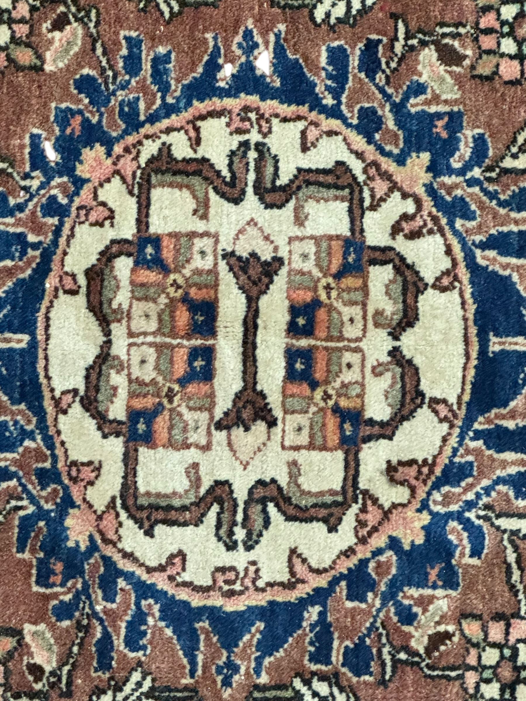 Persian Hamadan ground rug, central medallion design with a salmon pink field, accentuated by navy blue spandrels, surrounded by a stylised floral border in cream and blue tones