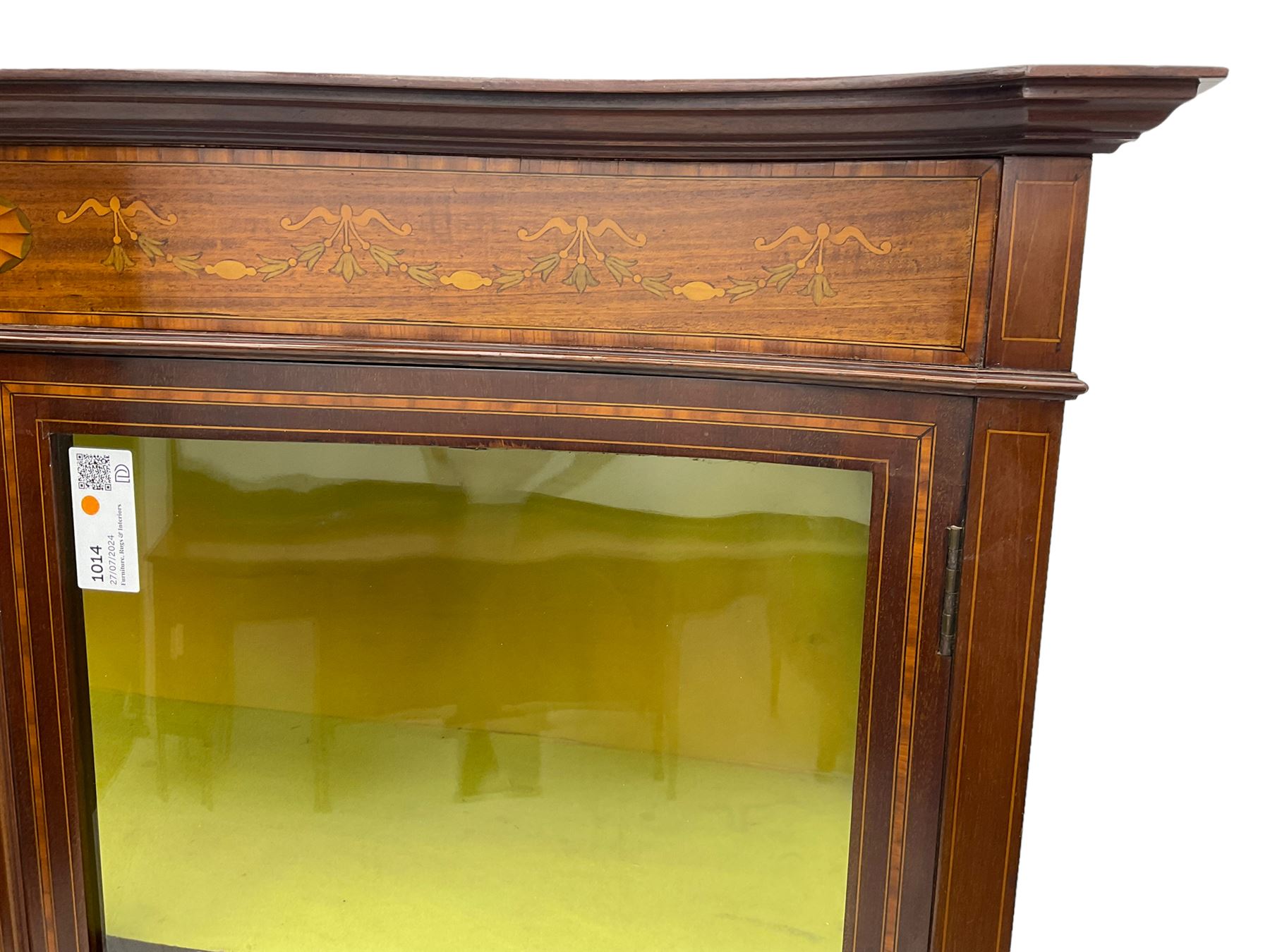 Edwardian inlaid mahogany serpentine display cabinet, projecting moulded cornice over figured frieze inlaid with tailing bellflowers and central fan motif, enclosed by two glazed doors, on square tapering supports with splayed terminals 