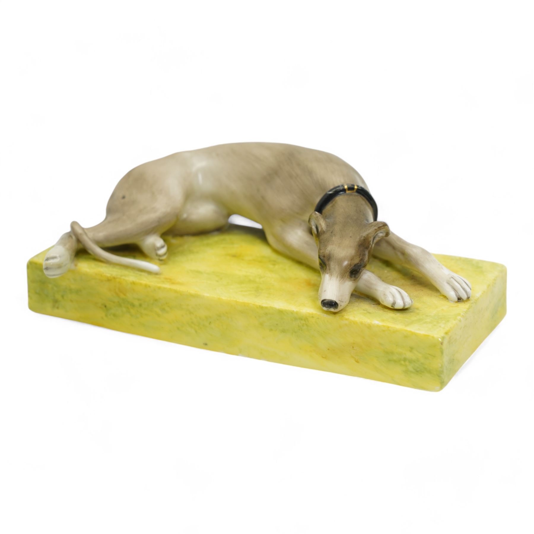 Late 19th century Sampson Hancock Derby porcelain model of a recumbent greyhound wearing a black collar, on a rectangular green painted base, initialled H.W with iron red marks beneath, L13.5cm x H4.5cm