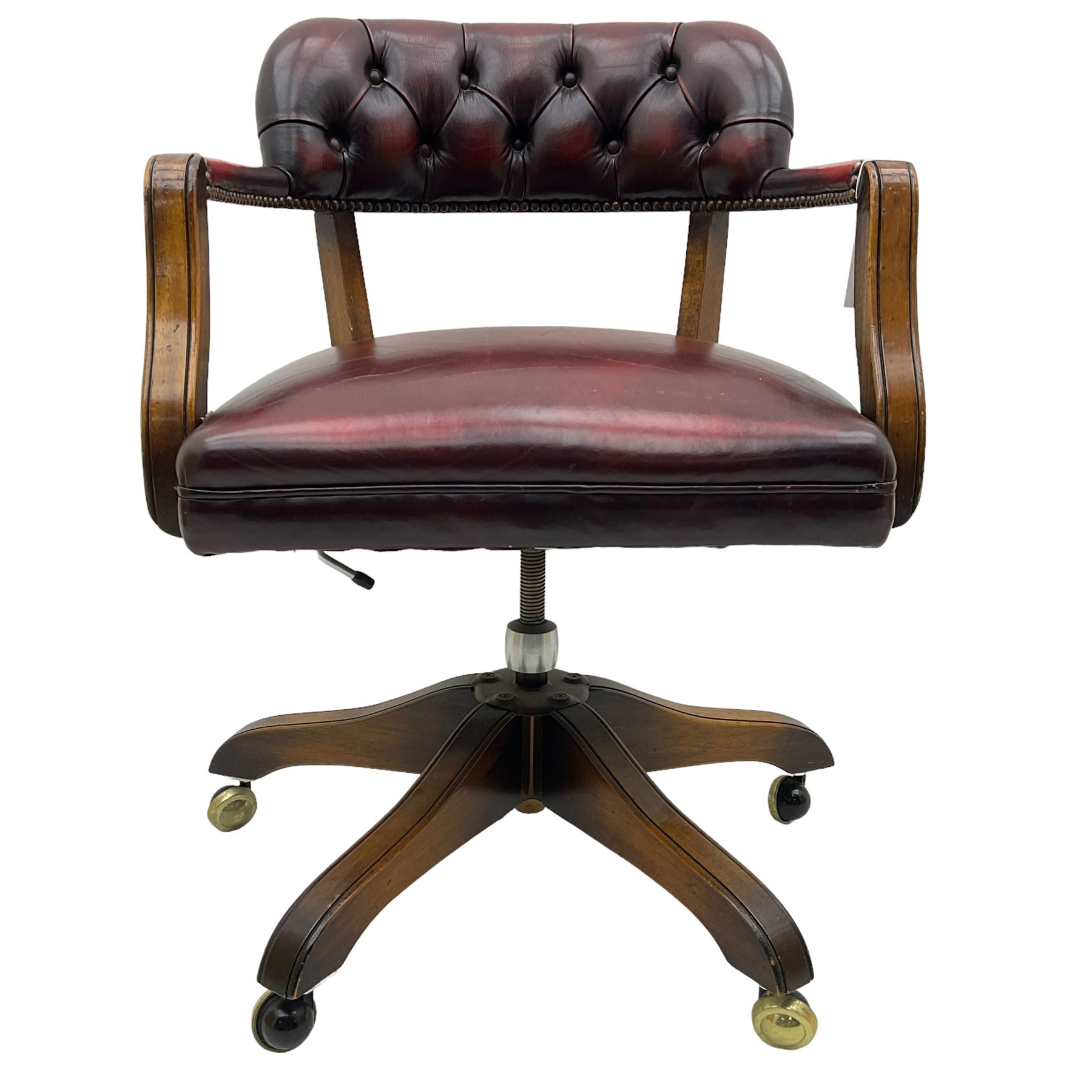 Mid 20th century leather swivel desk chair, oxblood button-tufted upholstery, wooden frame and armrests, on brass castor supports