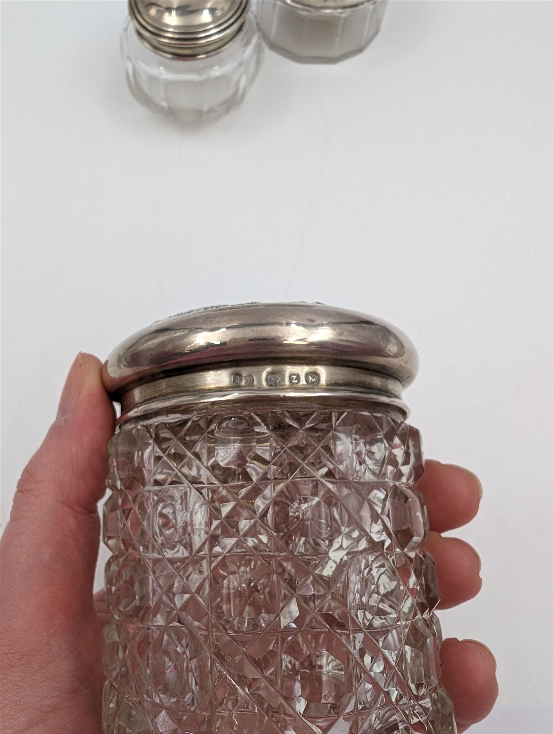 Three cut glass dressing table jars, each with hallmarked silver lids