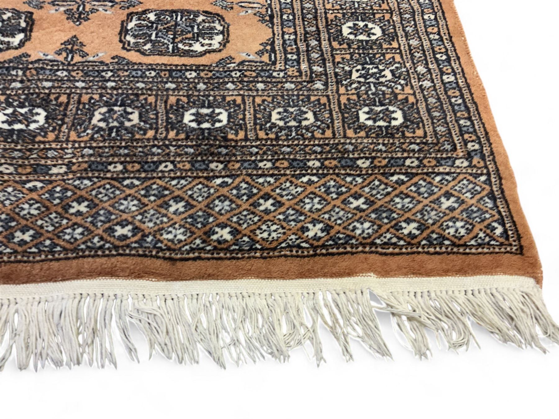 Afghan Bokhara rust ground rug, decorated with three columns of Gul motifs, the wide guard band with further scrolling and geometric designs (183cm x 129cm); together with a Persian design indigo ground rug (W170cm x 117cm)