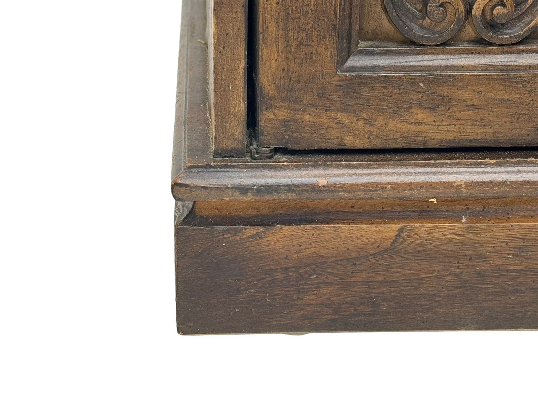 Mid 20th century oak bookcase cupboard, projecting cornice over three open shelves with subdivided sections and latticework uprights, two doors to the base with floral and scrollwork carvings and central brass handles, resting on a moulded plinth base