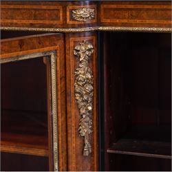 Victorian figured walnut and gilt metal mounted breakfront bookcase, satinwood banded top with gilt metal edging, the frieze inlaid with satinwood bands and mounted foliate castings, six shelves enclosed by four glazed doors each with cast foliate slips, the uprights decorated with ribbon tie and flower heads gilt metal mounts, on plinth base with egg and dart upper edge 